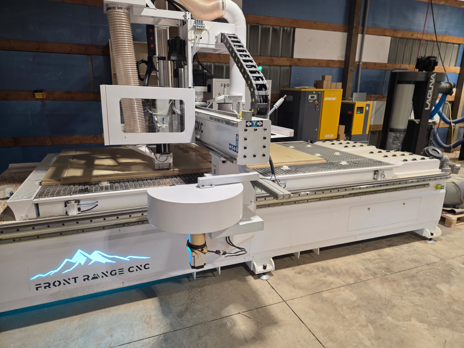 A Foundation CNC router on a real shop floor, teal mountain logo lit on its flank